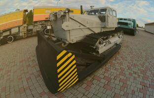 foto van een grijs bulldozer tussen de spoorweg treinen. sterk vervorming van de vissenoog lens