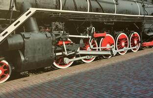 wielen van de oud zwart stoom- locomotief van Sovjet keer. de kant van de locomotief met elementen van de roterend technologie van oud treinen foto
