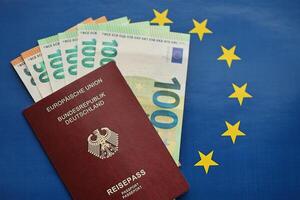 rood Duitse paspoort van Europese unie en geld Aan blauw vlag achtergrond dichtbij omhoog foto