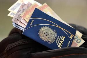 blauw braziliaans paspoort met geld en vliegmaatschappij kaartjes Aan toeristisch rugzak foto