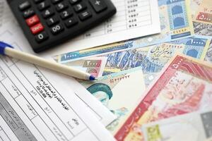 Iraans jaar- inkomen belasting terugkeer het formulier f20-25-006 klaar naar vullen Aan tafel met pen, rekenmachine en Iraans geld foto