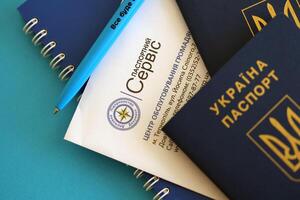 kiev, Oekraïne - november 27, 2023 paspoort onderhoud logo met Internationale oekraïens paspoort en pen foto