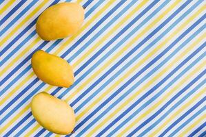 zomer versheid, rijp mango's Aan gestreept achtergrond foto