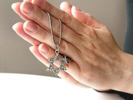 jong vrouw handen bidden met david's ster zilver hanger. jodendom. foto