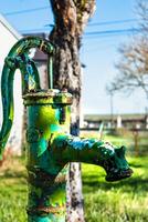 oud hand- water pomp Aan een goed in de tuin, gieter en besparing water, landelijk environnement foto