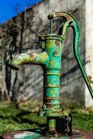 oud hand- water pomp Aan een goed in de tuin, gieter en besparing water, landelijk environnement foto