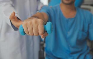 fysiotherapeut Mens geven oefening met halter behandeling over arm en schouder van atleet mannetje geduldig fysiek behandeling concept foto