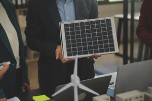 detailopname Bij tablet, ingenieurs richten Bij tablet met hun handen. naar gezamenlijk ontwerp de gebruik van hernieuwbaar energie met wind en zonne- energie. concept van gebruik makend van hernieuwbaar energie. foto