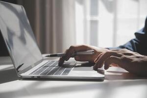 bijgesneden beeld van een jong Mens werken Aan zijn laptop in een koffie winkel, achterzijde visie van bedrijf Mens handen bezig gebruik makend van laptop Bij kantoor bureau, jong mannetje leerling typen Aan computer zittend Bij houten tafel foto