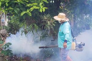 een Mens is werken beslaan naar elimineren muggen. in de regenen, seizoen worden voorzichtig van muggen en beschermen tegen dengue koorts verspreiding. concept van gezondheidszorg foto