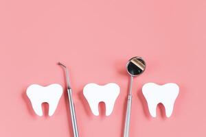 tandheelkundig zorg concept. tandheelkundig gereedschap Aan roze achtergrond. gelukkig tandarts dag. papier besnoeiing mockup van tand. foto