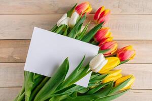 kleurrijk tulpen boeket en groet kaart Aan houten achtergrond. vakantie geschenk. foto