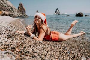 vrouw reizen zee. gelukkig toerist genieten nemen afbeelding Aan de strand voor herinneringen. vrouw reiziger in de kerstman hoed looks Bij camera Aan de zee baai, sharing reizen avontuur reis foto