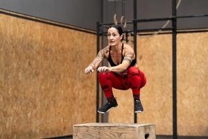 sterk sportief vrouw jumping in doos in een Sportschool foto