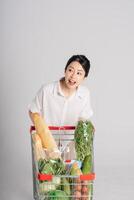 glimlachen vrouw gelukkig voortvarend een supermarkt kar, geïsoleerd Aan wit achtergrond foto