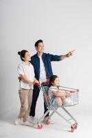 beeld van Aziatisch familie voortvarend een supermarkt kar terwijl winkelen, geïsoleerd Aan wit achtergrond foto