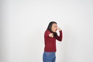 jong Aziatisch vrouw in rood t-shirt ruiken iets stinkend en walgelijk geïsoleerd Aan wit achtergrond foto