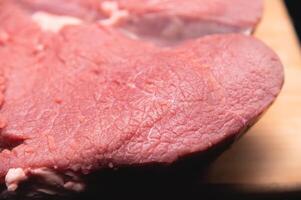 stuk van rauw vlees leugens Aan een snijdend bord Aan een donker achtergrond. detailopname van rundvlees vlees vezels foto