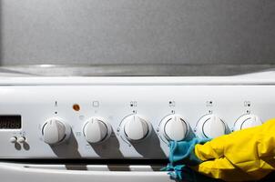 vrouw het wassen gas- fornuis, detailopname. vrouw hand- in handschoen doekjes de gas- paneel met vod, kopiëren ruimte. schoonmaak van keuken appartementen foto