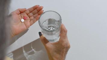 ouderen vrouw drinken pillen. detailopname van vrouw handen Holding een glas van water en geneesmiddel, wit achtergrond kopiëren ruimte. behandeling concept, ziekte pensioen foto