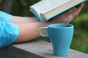 vrouw lezing boek buitenshuis, koffie kop Bij middag foto