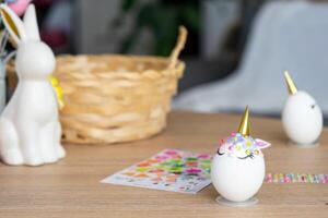 Pasen ambacht - siert een ei in de het formulier van een eenhoorn met strass steentjes, Hoorn, bloemen in de interieur van een huis foto