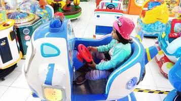 semarang, Indonesië - februari, 2024 - een meisje ritten een vliegtuig spel Aan de speelplaats foto