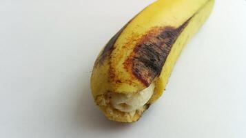 geel banaan met bruinig zwart vlekken Aan een wit achtergrond foto