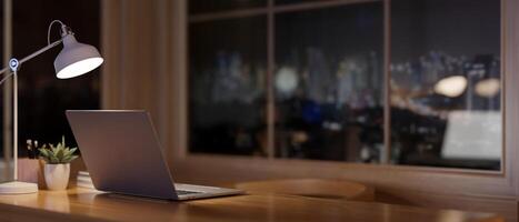 een laptop Aan een bureau in een hedendaags kamer Bij nacht, met een visie van de stad wolkenkrabbers Bij nacht. foto