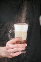 persoon sprenkeling suiker Aan een koffie kop foto