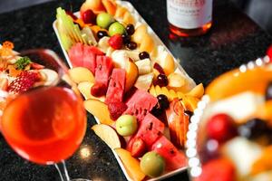 dienblad van vers fruit en glas van wijn Aan tafel foto