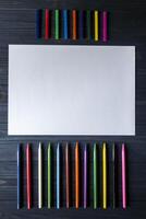 palet van veelkleurig potloden en de vel van wit papier Aan donker blauw houten bureau. foto