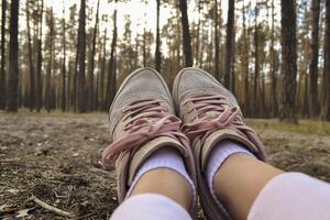 een vrouw voeten in sportschoenen tegen een Woud achtergrond. een meisje ontspannende in de Woud. foto