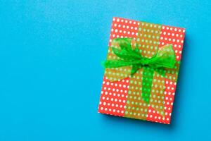 verpakt Kerstmis of andere vakantie handgemaakt Cadeau in papier met groen lint Aan blauw achtergrond. Cadeau doos, decoratie van geschenk Aan gekleurde tafel, top visie met kopiëren ruimte foto