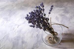 de boeket van droog lavendel in een glas vaas Aan de bureau. top visie. foto