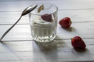 rijp aardbeien en glas van room Aan een wit houten tafel. de gezond voedsel. foto