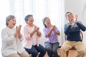 senior vrouwtjes en mannetje zittend Aan bank. ouder mensen zijn luisteren en genieten vergadering focus groep Bij leven kamer. blij zorgeloos gepensioneerd senior vrienden genieten van ontspanning Bij bijna huis. foto