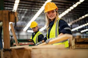 vrouw schoonmaak hout hout in donker magazijn industrie. team arbeider timmerman vervelend veiligheid uniform en moeilijk hoed werken en controle de kwaliteit van houten producten Bij werkplaats productie. foto