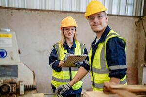 arbeider timmerlieden werken in machines naar besnoeiing hout hout. Mens en vrouw zijn bouwen met hout in een werkplaats. twee ambachtslieden of klusjesmannen werken met timmerman gereedschap of elektrisch machines. foto