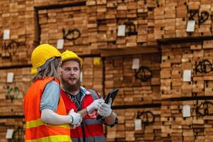 arbeiders timmerman vervelend veiligheid uniform en moeilijk hoed werken en controle de kwaliteit van houten producten Bij werkplaats productie. Mens en vrouw arbeiders hout in donker magazijn industrie. foto