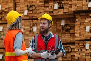 arbeiders timmerman vervelend veiligheid uniform en moeilijk hoed werken en controle de kwaliteit van houten producten Bij werkplaats productie. Mens en vrouw arbeiders hout in donker magazijn industrie. foto