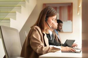 Aziatisch operator werken in kantoor. jong vriendelijk operator vrouw middel met headsets werken in een telefoontje centrum. foto