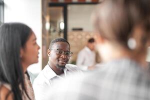 focus van slim Afrikaanse zakenman. verschillend medewerkers verzameld in kantoor hebben pret brainstorming terwijl bespreken nieuw ideeën project. multiraciaal collega's vergadering Bij coworking ruimte Oppervlakte. foto