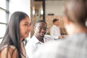 focus van slim Afrikaanse zakenman. verschillend medewerkers verzameld in kantoor hebben pret brainstorming terwijl bespreken nieuw ideeën project. multiraciaal collega's vergadering Bij coworking ruimte Oppervlakte. foto