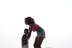 gemengd ras Afrikaanse en Aziatisch moeder en jongen is spelen Bij de buitenshuis Oppervlakte. glimlachen gelukkig familie hebben pret rennen Aan de strand. portret van mam en kind levensstijl met een uniek kapsel. foto