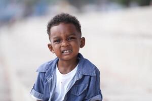 gemengd ras Afrikaanse en Aziatisch jongen is spelen Bij de buitenshuis Oppervlakte. glimlachen gelukkig jongen heeft pret rennen Aan de strand. portret van jongen levensstijl met een uniek kapsel. foto