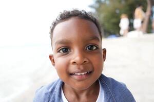 gemengd ras Afrikaanse en Aziatisch jongen is spelen Bij de buitenshuis Oppervlakte. glimlachen gelukkig jongen heeft pret rennen Aan de strand. portret van jongen levensstijl met een uniek kapsel. foto