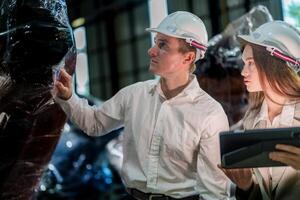 verkoop manager en fabriek eigenaar in pakken onderhandelen verkoop robots gebruikt in de fabriek. bedrijf ingenieurs vergadering en controle nieuw machine robot. arbeiders wandelen Bij magazijn lassen machine. foto