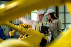 fabriek ingenieurs inspecteren Aan machine met slim tablet. arbeider werken Bij machine robot arm. de lassen machine met een afgelegen systeem in een industrieel fabriek. kunstmatig intelligentie- concept. foto