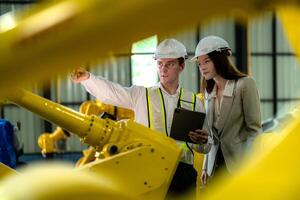 fabriek ingenieurs inspecteren Aan machine met slim tablet. arbeider werken Bij machine robot arm. de lassen machine met een afgelegen systeem in een industrieel fabriek. kunstmatig intelligentie- concept. foto